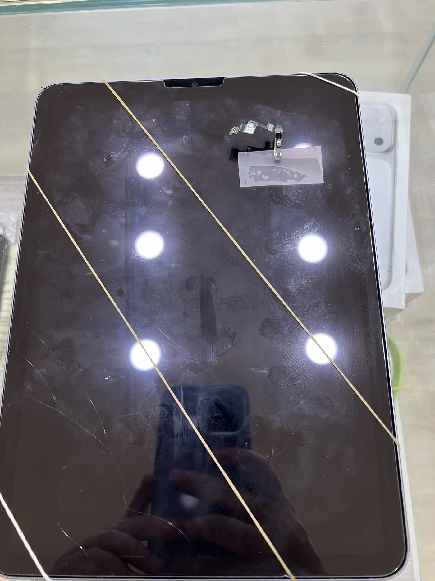 iPad Air 更換電源鍵排線後，以橡皮筋綑綁固定等待螢幕膠定型，螢幕上放著拆下的舊按鍵排線