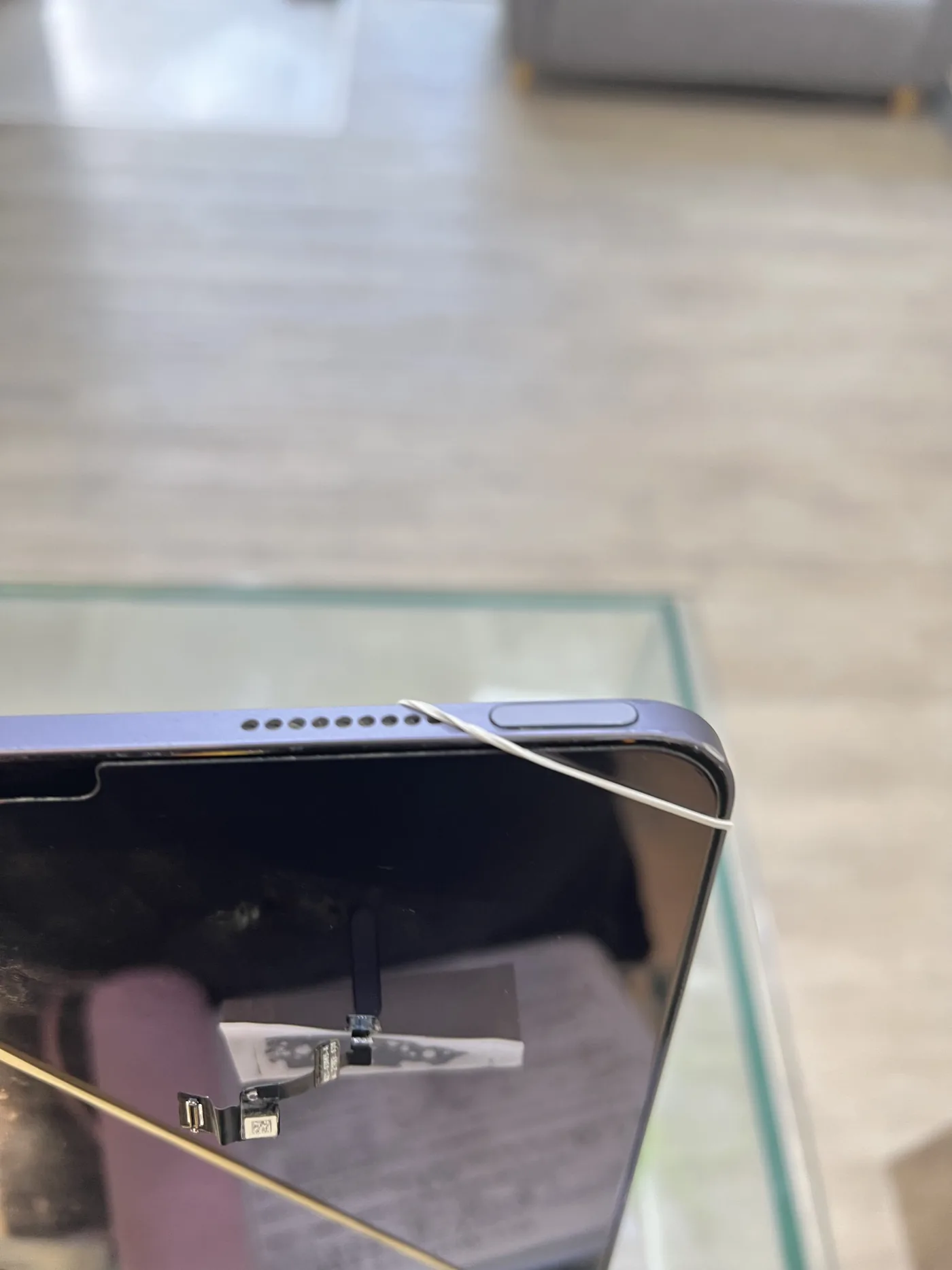 iPad Air 頂端的電源鍵（整合 Touch ID）與揚聲器孔特寫，機身以橡皮筋固定