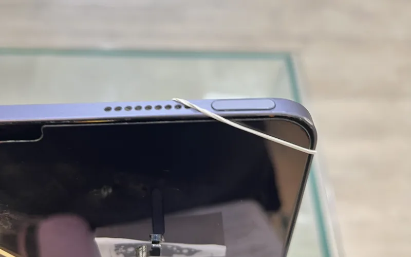 iPad Air 頂端的電源鍵（整合 Touch ID）與揚聲器孔特寫，機身以橡皮筋固定