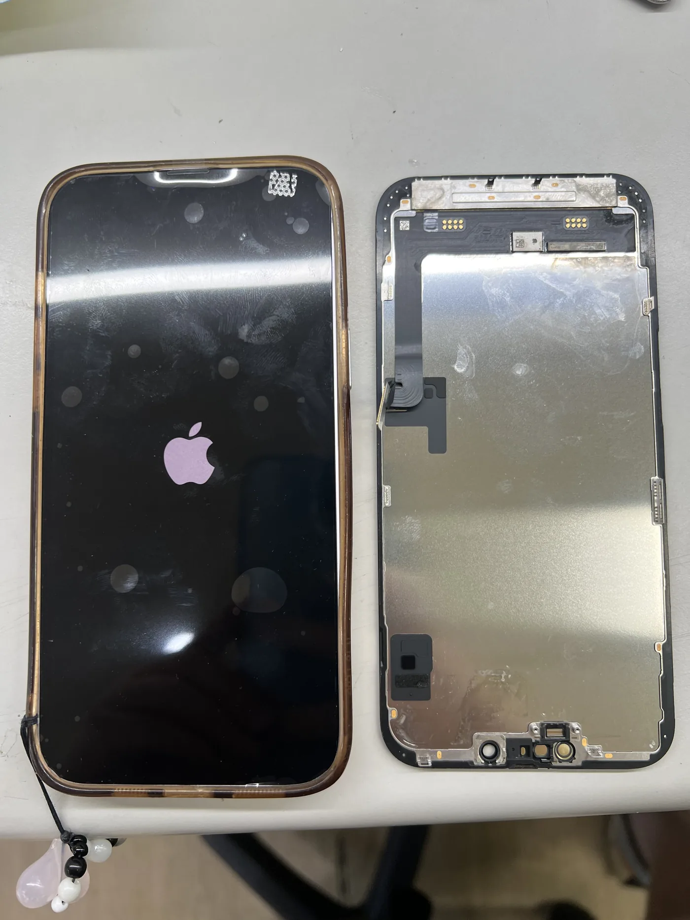 iPhone 進水後更換螢幕，左邊為換上新螢幕後開機顯示 Apple 標誌，右邊為拆下的舊螢幕總成背面