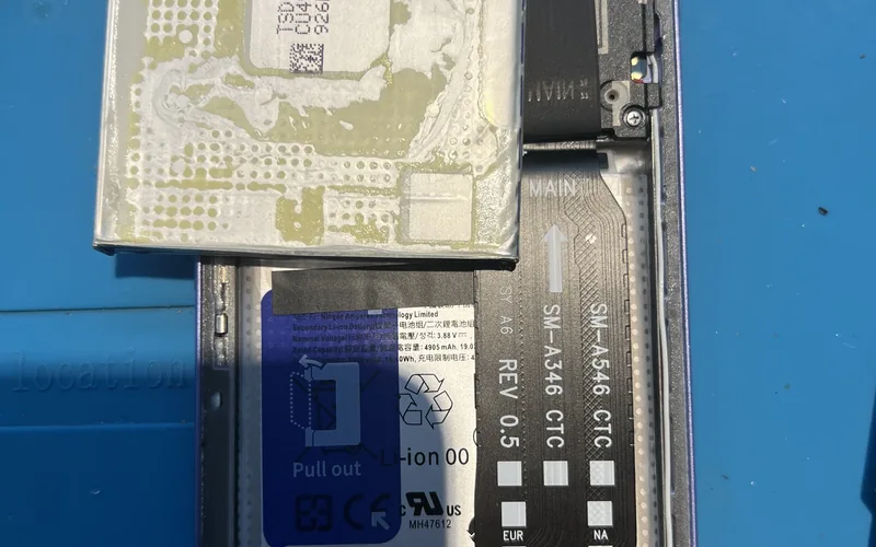 Samsung Galaxy A54 拆開背蓋更換電池，舊電池背面布滿殘膠，機身內已裝上新電池，排線印有 SM-A546