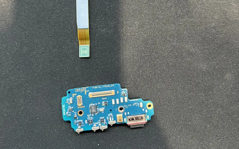 Samsung Galaxy S23 Ultra 拆下的尾插小板與主副板連接排線，放在深色維修墊上