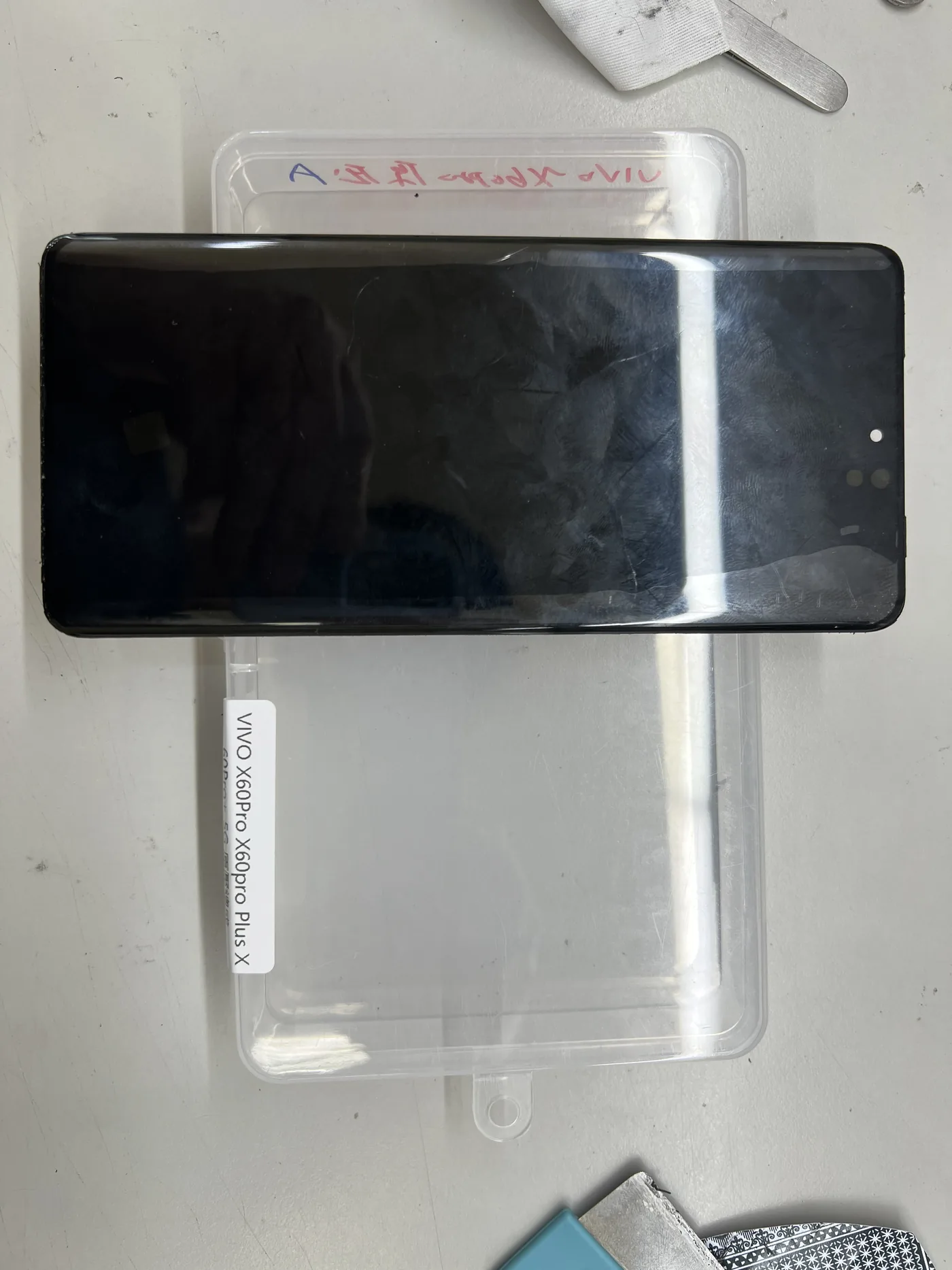 vivo X60 Pro 曲面螢幕總成放在零件包裝盒上，可見曲面邊緣與包裝標示