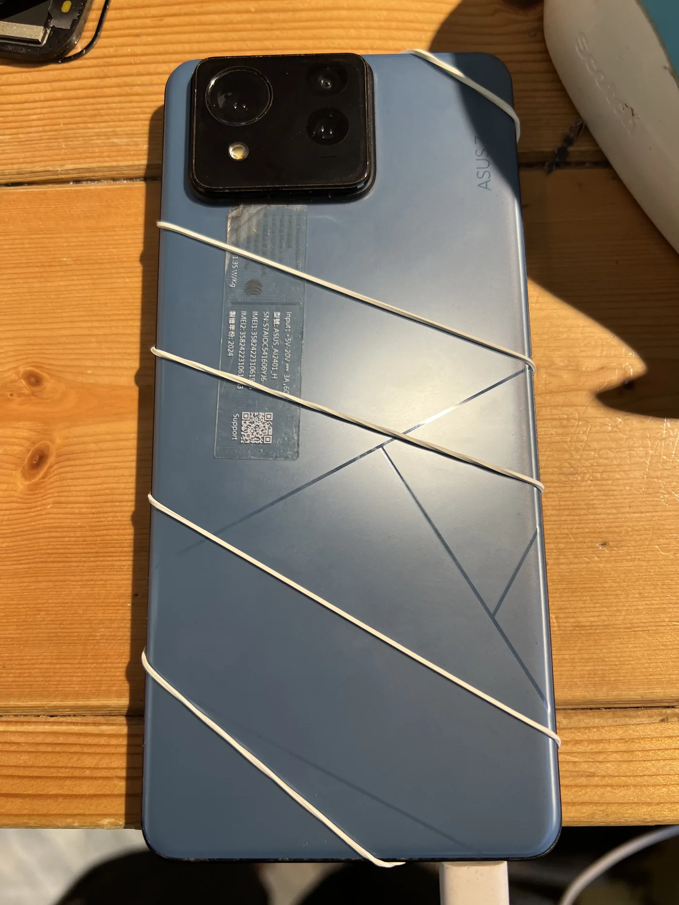 ASUS Zenfone 11 Ultra 機身背面，維修後以橡皮筋固定壓合
